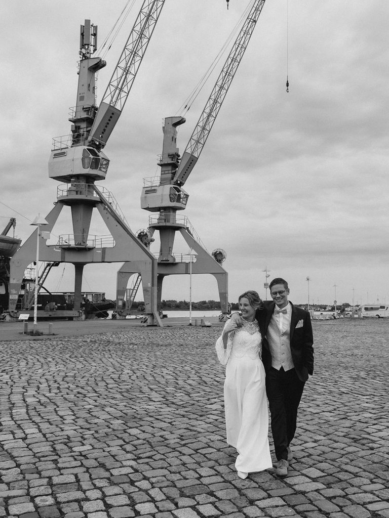 Hochzeitspaar am Rostocker Stadthafen mit Kränen in Hintergrund