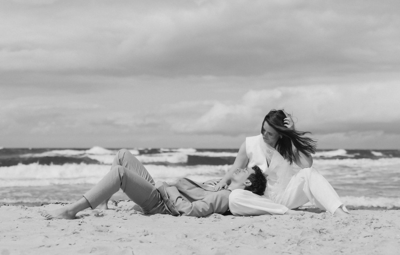 Brautpaar sitzt am Strand von Ahrenshoop mit dem Meer im Hintergrund